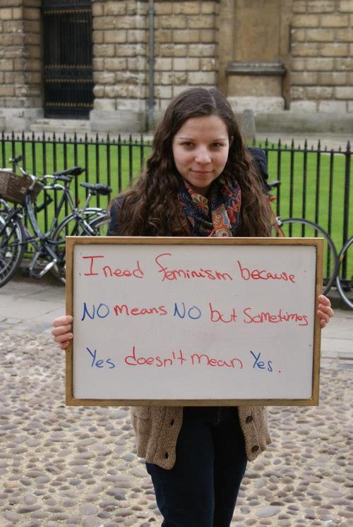 A photo of a feminist holding a medium-sized whiteboard that says, "I need feminism because no means no but sometimes yes doesn't mean yes."