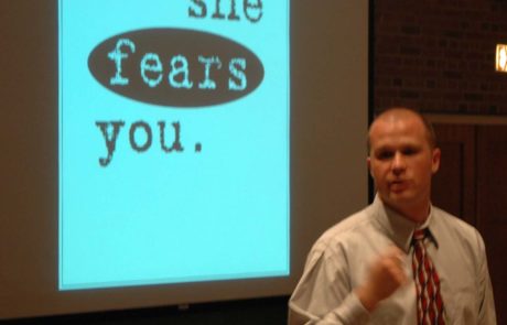 Keith Edwards giving his "She Fears You" presentation to first-year students. In the background is a screen that says "She Fears You" in large letters.