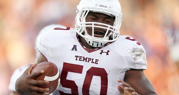 A photograph of Praise Martin Oguike in full football gear and running the ball.