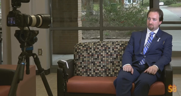 A still photo of Jonathan Taylor sitting on a couch as he is about to be interviewed by Studio Brule.