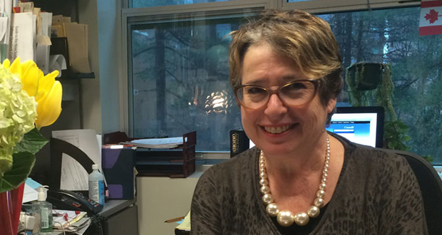 A photo of Professor Judy Haiven at her desk. She seems happy.